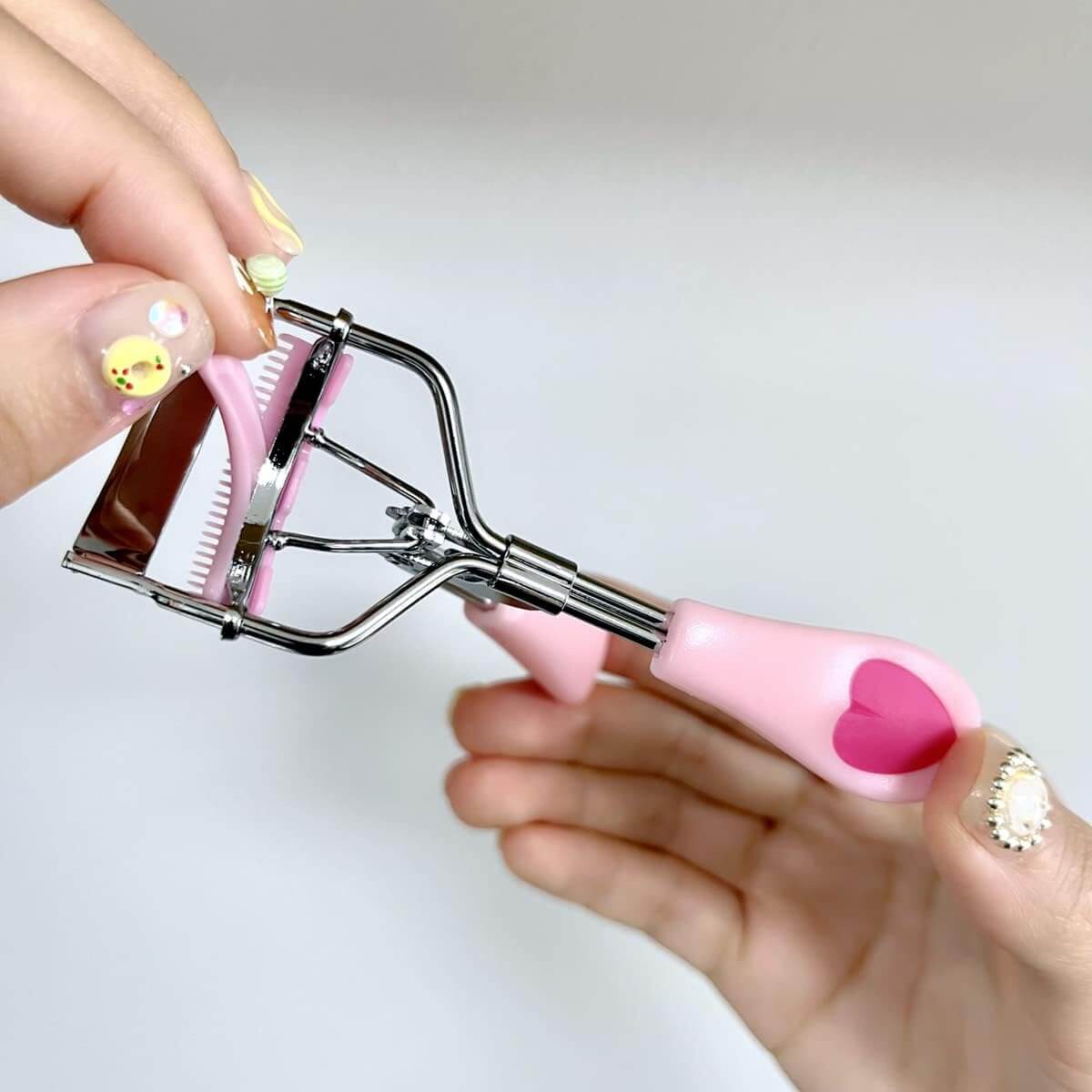 Axiva Rostfri Ögonfransböjare med rosa handtag som ger perfekt böj utan skador.